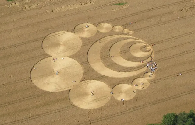 Vista aérea de un elaborado círculo geométrico realizado sobre un campo de trigo dorado.