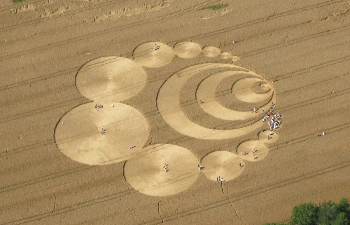 Vista aérea de un elaborado círculo geométrico realizado sobre un campo de trigo dorado.