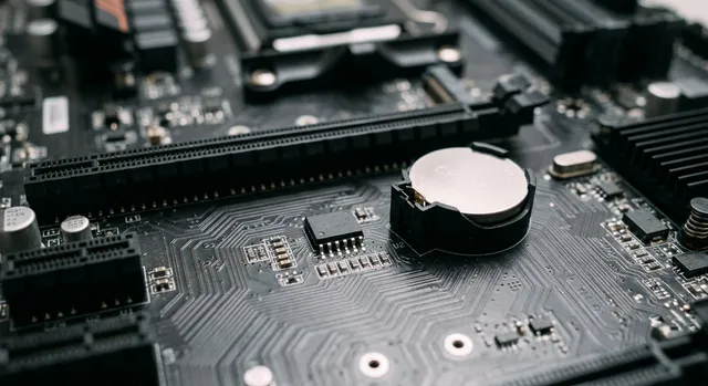 Placa base de ordenador mostrando en detalle el chip de memoria EEPROM y la pila CMOS.