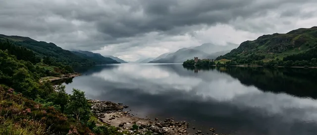 Vista panorámica y brumosa del lago Ness en Escocia con las ruinas del castillo de Urquhart en la orilla.