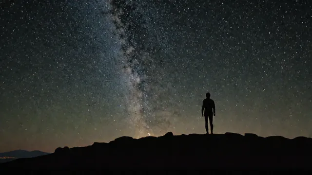 Persona de espaldas contemplando el cielo estrellado en la noche.