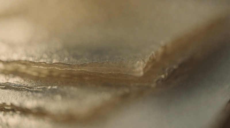 Stack of translucent ink sheets under soft light, showing font layering