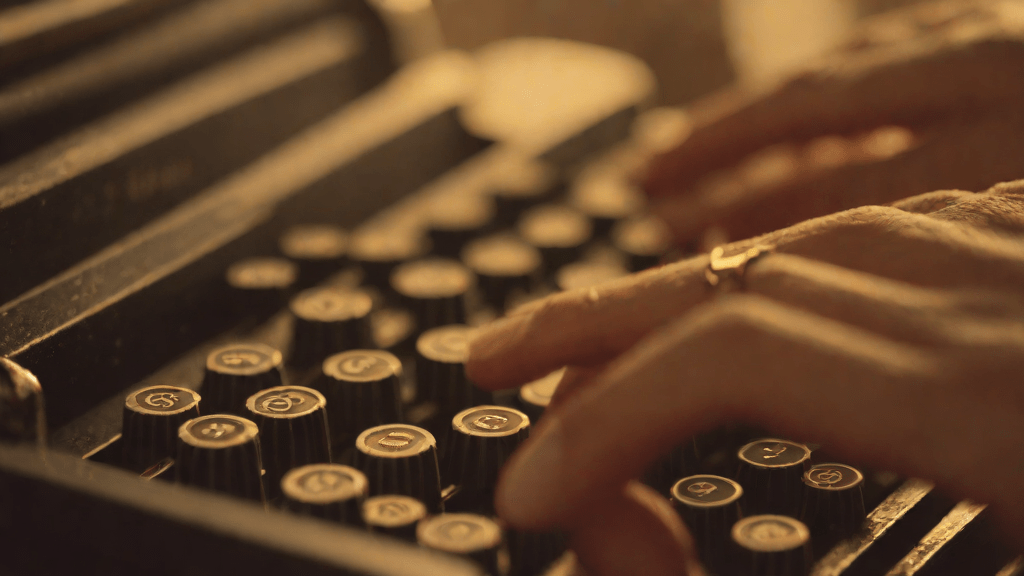 Hands typing on an old typewriter with glowing ink in warm light