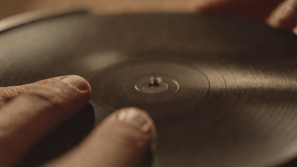 Mano con un vinilo antiguo mostrando voces fantasma en sus grabados