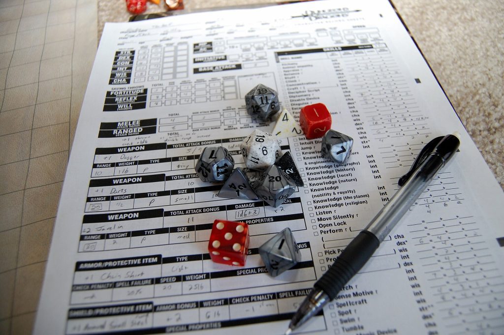 Mesa de juego de rol con un conjunto de dados poliédricos de colores y una hoja de personaje.