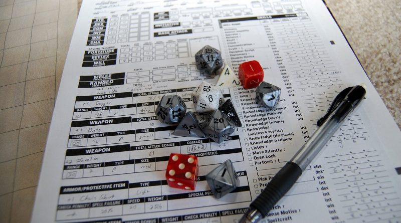 Mesa de juego de rol con un conjunto de dados poliédricos de colores y una hoja de personaje.